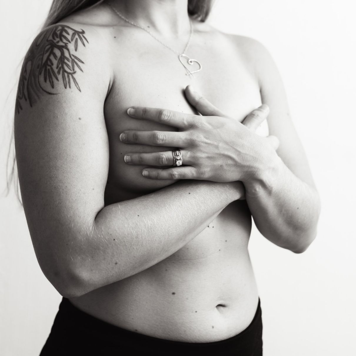woman with her arms crossed over her chest wearing a silber necklace with a heart pendant